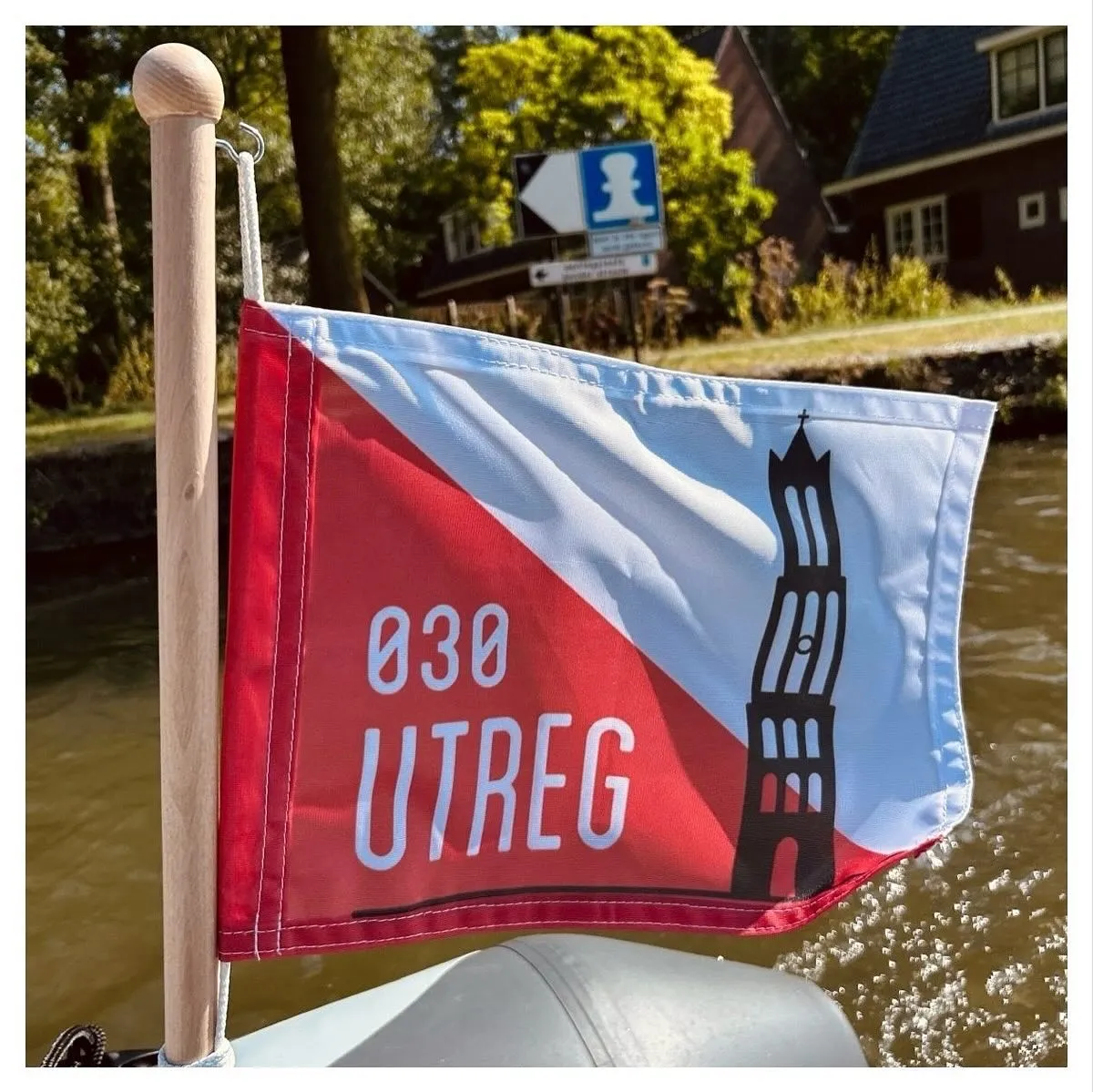 Klein vlaggetje met de rood-witte Utrechtse vlag, de Domtoren en de tekst 030 UTREG, aan een boot